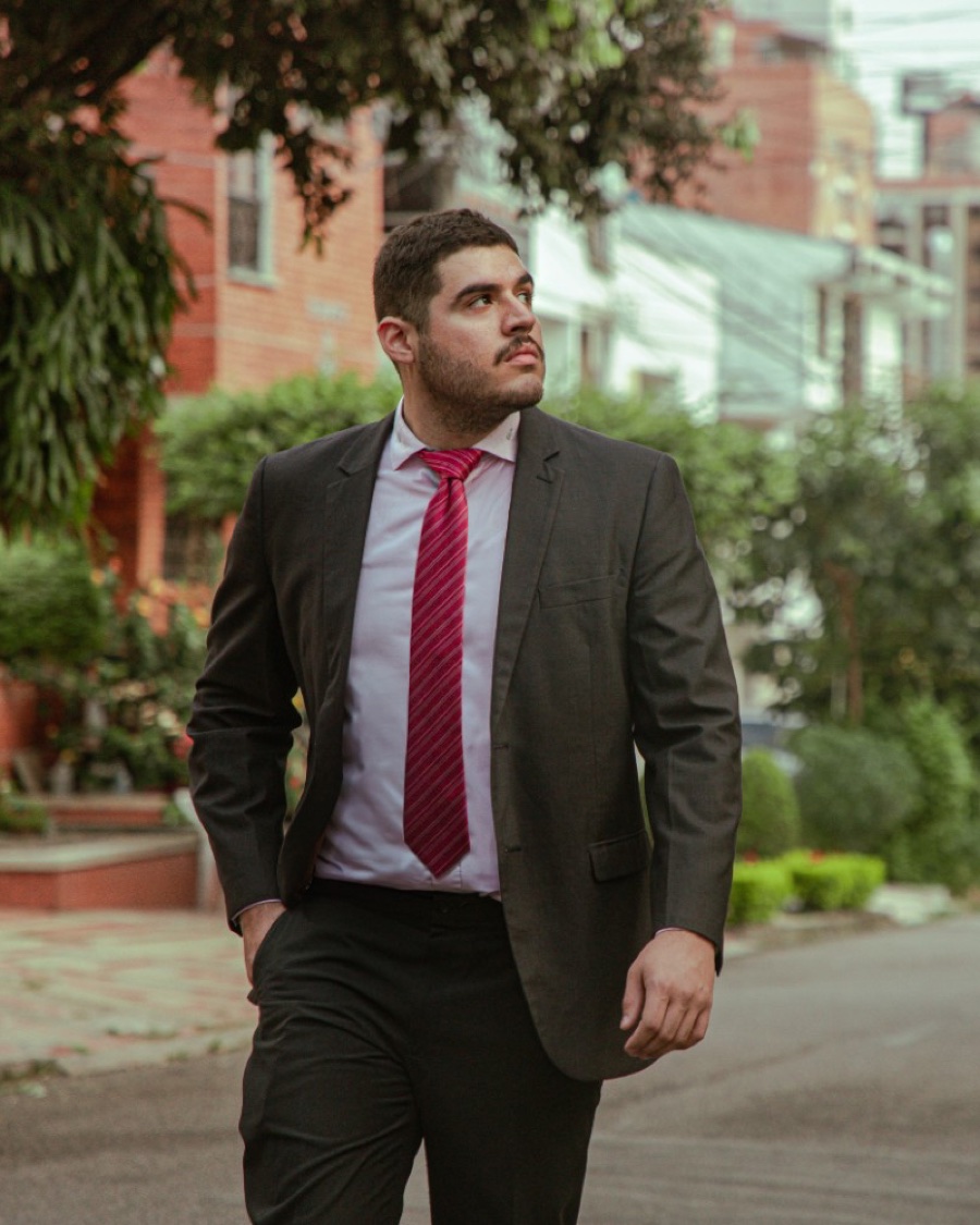 Andrés Peñaranda, de traje y corbata, señalando mientras camina por la calle